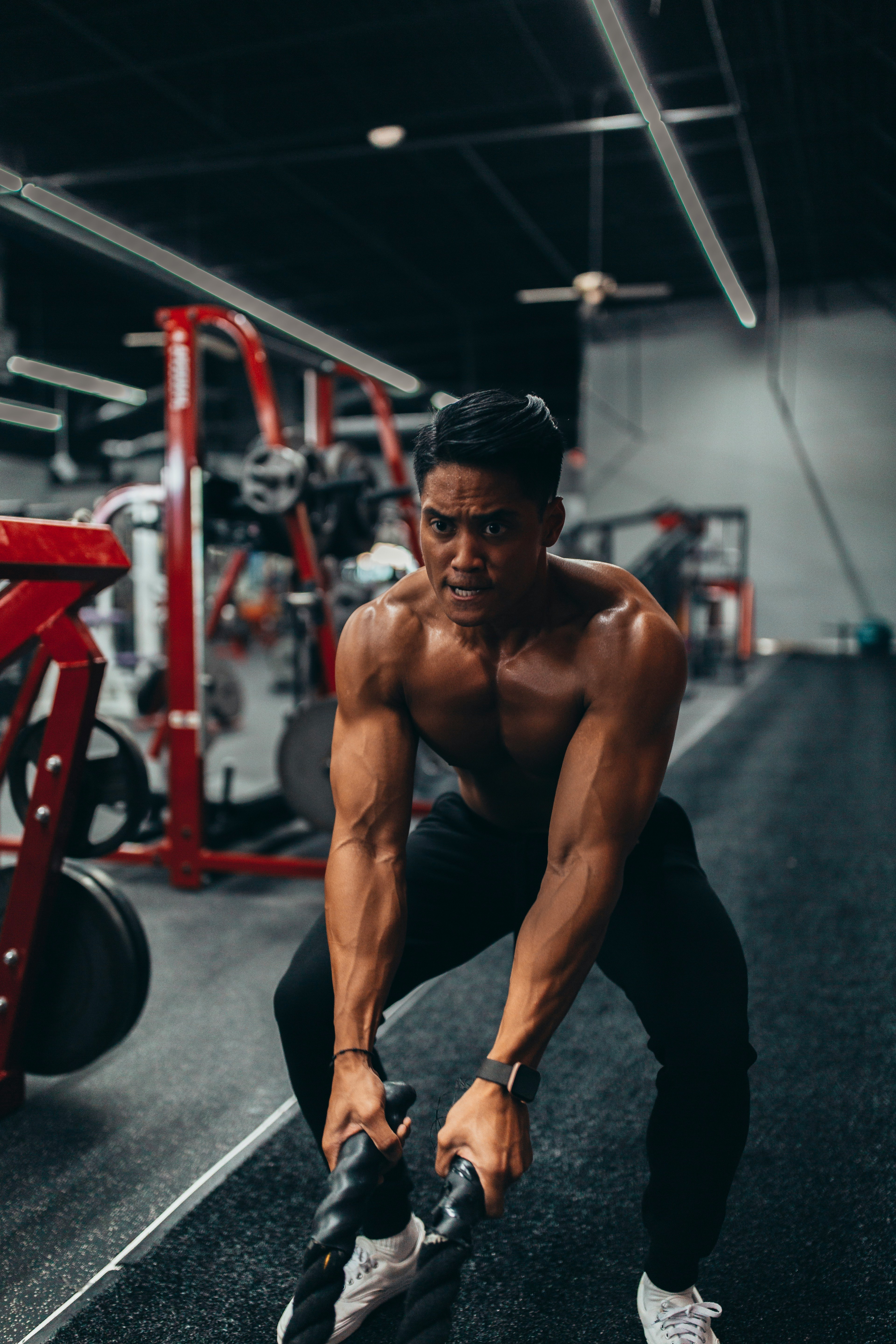 muscled man holding two black ropes